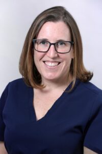 Smiling woman with glasses in blue attire.
